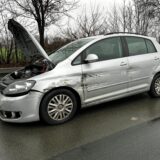 Ein silberfarbenes Auto steht verschrammt und mit geöffneter Motorhaube  am Rand der Autobahn 1.