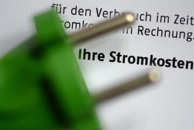 Ein grüner Stromstecker liegt auf einer Stromrechnung.