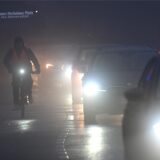 Fahrräder und Autos fahren am Morgen durch den Nebel.