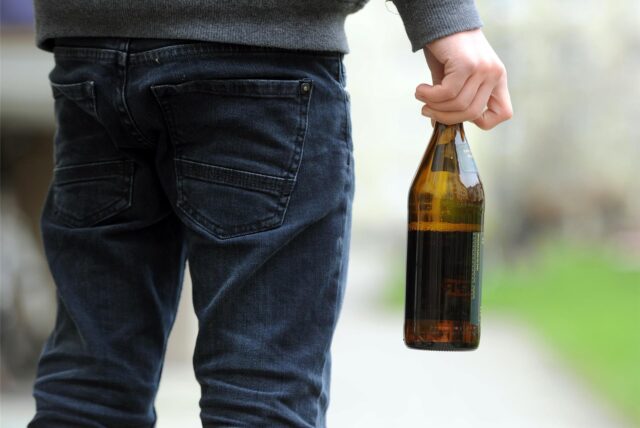 Person mit einer Flasche in der Hand.