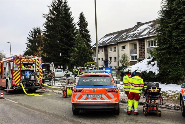 Einsatzkräfte stehen vor einem Mehrfamilienhaus im Ennepe-Ruhr-Kreis.