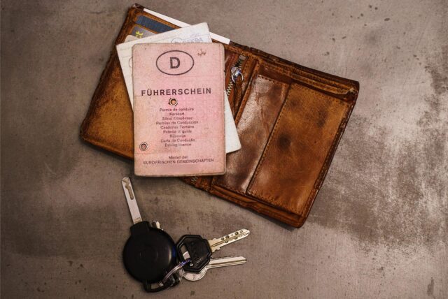 Ein «rosa Führerschein», ein Autoschlüssel, eine Geldbörse und ein Fahrzeugschein liegen auf dem Tisch.