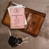 Ein «rosa Führerschein», ein Autoschlüssel, eine Geldbörse und ein Fahrzeugschein liegen auf dem Tisch.