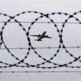 Ein Flugzeug startet – fotografiert durch einen Stacheldraht an einem Flughafenzaun