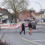 Menschen laufen über die Bahnhofstraße in Bönen. Im Hintergrund sieht man Baustellenbaken und einen Bagger.