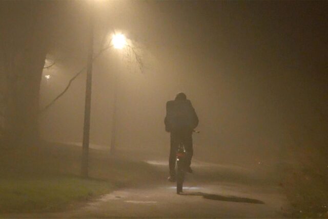Ein Radfahrer fährt bei dichtem Nebel durch einen Park.
