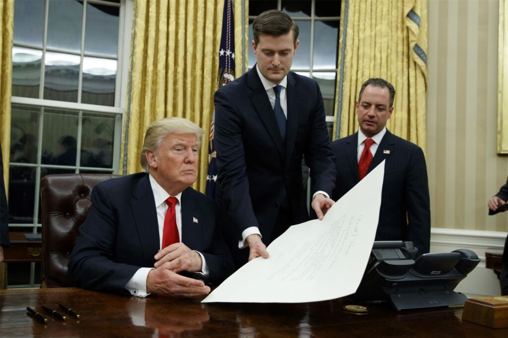 Staatssekretär Rob Porter (M) legt dem neuen US-Präsidenten Donald Trump (l) am 20.01.2017 nach der Amtsübernahme im Oval Office des Weißen Hauses in Washington (USA) die Ernennungsurkunde für den neuen Verteidigungsminister Mattis zur Unterzeichnung auf den Tisch - rechts Stabschef Reince Priebus.