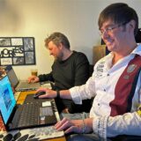 Marius Gellert (vorne) und Robin Winkelmann sitzen an Laptops.