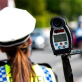 Eine Polizistin misst mit einem Laser die Geschwindigkeit eines Autos.
