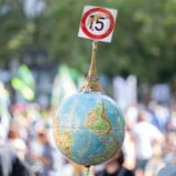 Einen Globus mit einem Miniatur-Eiffelturm und dem 1,5-Grad Ziel des Pariser Klimaschutzabkommens trägt ein Mann auf der Demonstration vor der Alten Oper in Frankfurt.