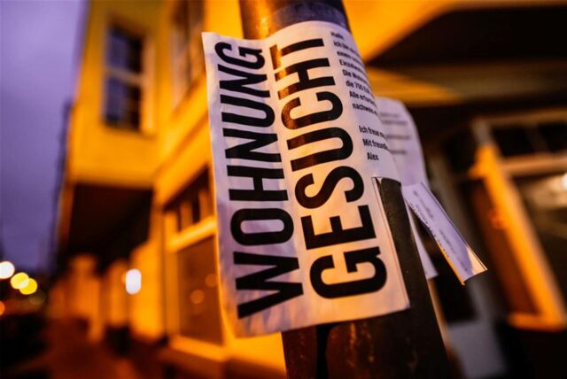 Ein Zettel mit der Aufschrift „Wohnung gesucht“ hängt an einer Säule.
