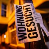 Ein Zettel mit der Aufschrift „Wohnung gesucht“ hängt an einer Säule.