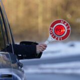 Eine Polizistin hält eine Anhaltekelle aus dem Seitenfenster eines Einsatzfahrzeugs.