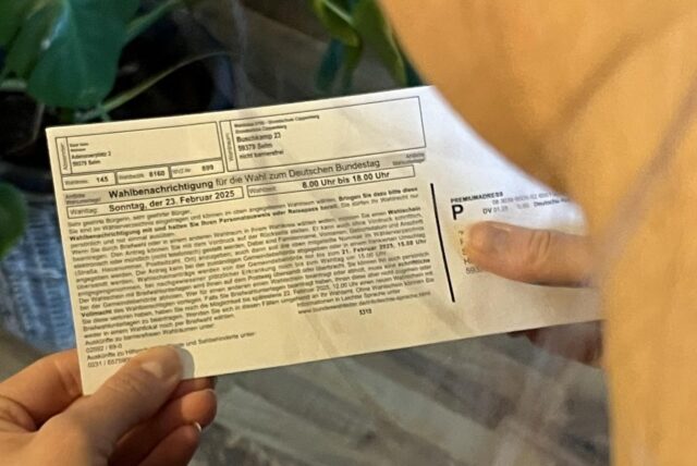 Eine Frau hält eine Wahlbenachrichtigung in den Händen.
