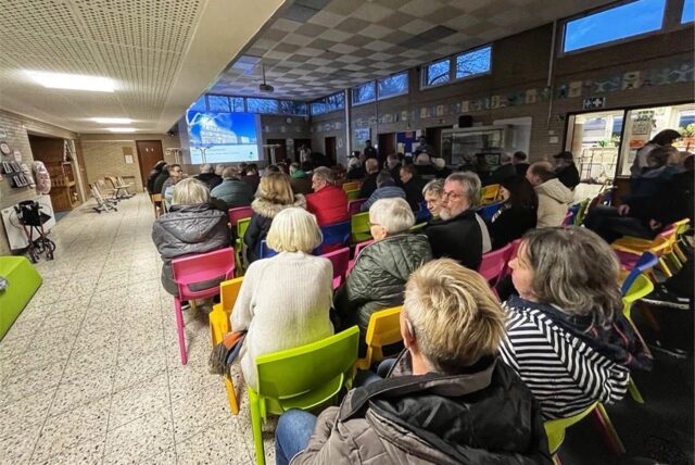 Bürgerinnen und Bürger sitzen in der Nordschule auf bunten Stühlen.