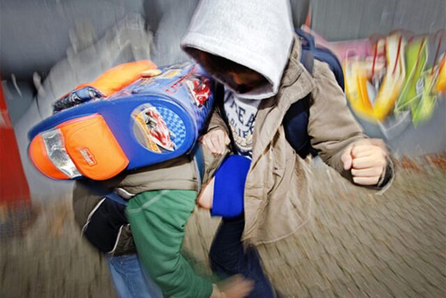 Zwei Schüler prügeln sich auf einem Schulhof.