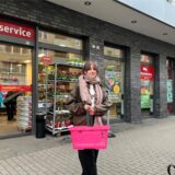 Eine Frau steht mit einem pinken Einkaufskorb vor dem Rewe-Markt auf der Dortmunder Saarlandstraße.