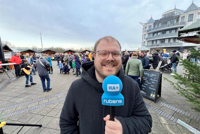 Mathias Gaumann, Reporter des Hellweger Anzeigers, steht mit Mikron in der Marina Rünthe. Im Hintergrund sind Besucher des Hafenfeuers 2025 zu sehen.