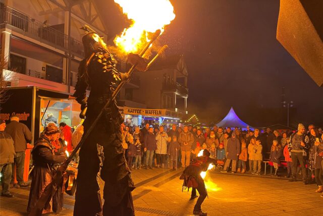 Der Walk-Act um Thyriorn, den Gigant auf Stelzen, spuckt Feuer.
