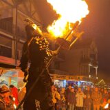 Der Walk-Act um Thyriorn, den Gigant auf Stelzen, spuckt Feuer.