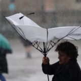 Mit einem Regenschirm versucht sich eine Frau bei stürmischem Wetter gegen den Regen zu schützen.