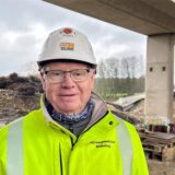 Karl-Heinz Bühring, der 73-Jährige Sprengmeister, steht vor dem äußeren Teilbauwerk der Liedbachtalbrücke in der Massener Heide in Unna. Der Sprengmeister trägt eine gelbe Warnweste und einen weißes Schutzhelm.