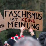 Menschen halten bei einer Kundgebung Schilder hoch.