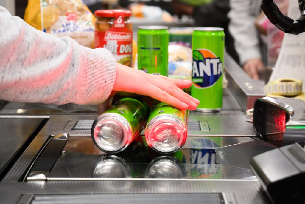 Eine Kassiererin scannt Fanta-Getränkedosen an der Kasse eines Supermarktes. Eine Kassiererin scannt Fanta-Getränkedosen an der Kasse eines Supermarktes.