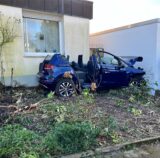 Ein völlig demoliertes blaues Auto mit abgeschnittenem Dach steht in dem Vorgarten eines Hauses im Akazienweg in Unna