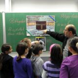 Lehrer und Kinder vor einer Tafel beim Islamunterricht.