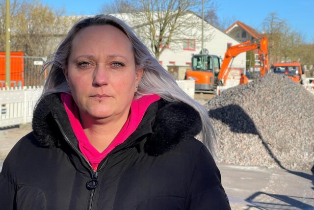 Dina Stöckner (43) schaut mit einem neutralen Blick in die Kamera. Im Hintergrund die Baustelle am Südfeld in der Unschärfe.