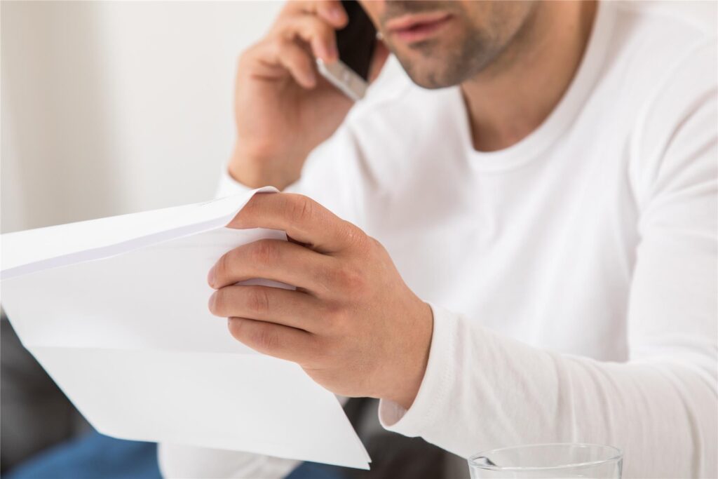Ein Mann telefoniert, während er einen Brief in der Hand hält. Ein Mann telefoniert, während er einen Brief in der Hand hält.