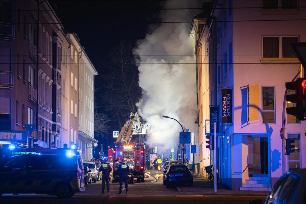 Einsatzkräfte der Feuerwehr Dortmund löschen ein Feuer, dichter Rauch kommt aus der Brandwohnung.