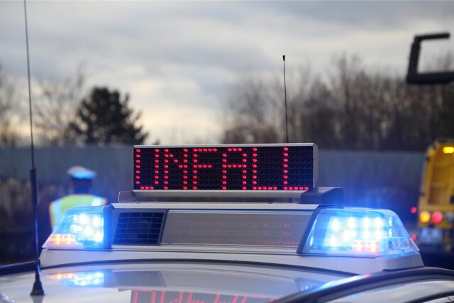 Ein Schild auf einem Polizeiauto warnt vor einem Unfall.