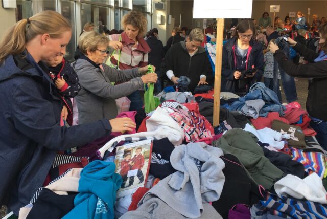 Frauen stöbern in einem Kleiderhaufen.