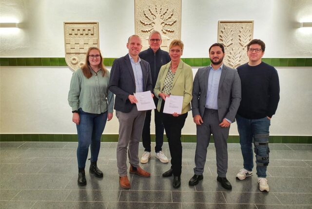 Vertreter eines Hochbauunternehmens haben sich mit Bürgermeisterin und Verwaltungsmitarbeitern aus Holzwickede für ein Foto aufgestellt.