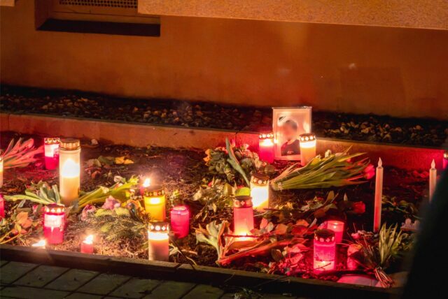 Eine Gedenkstelle mit Kerzen, einem Foto und Blumen an der Wohnung der Getöteten in Huckarde.