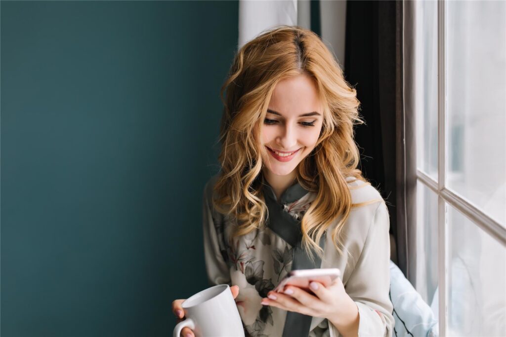 Junge Frau schaut auf ihr Smartphone Junge Frau schaut auf ihr Smartphone