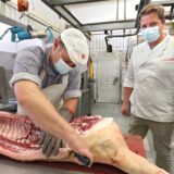 Metzgermeister Christian Rafalcik (r.) sieht einem Mitarbeiter beim Zerlegen einer Schweinhälfte in seinem Betrieb in Fröndenberg zu.