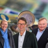 Es sind verschiedene Geldscheine und Münzen abgelichtet. Im Vordergrund sieht man Frank Röhr, Vorstandsvorsitzender der Sparkasse UnnaKamen. Ines Brüggemann, Ines Brüggemann, Geschäftsführerin der Wirtschaftsbetriebe Unna (WBU). Jürgen Schäpermeier, Geschäftsführer der Stadtwerke Unna. Frank Peters, Betriebsleiter der Stadtbetriebe Unna und Horst Bresan, Geschäftsführer von Unna Marketing.