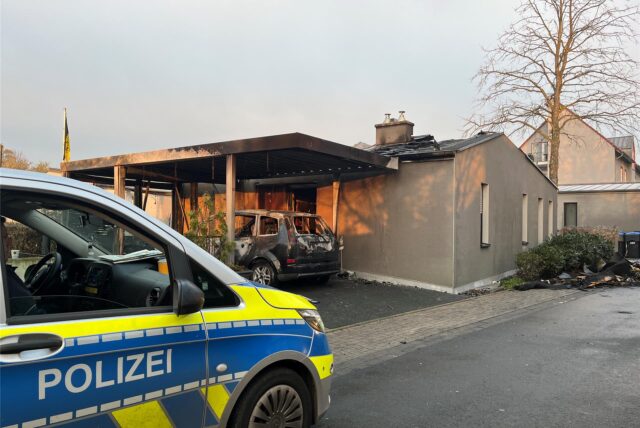 Ein Auto der Polizei steht vor einem Bungalow, der abgebrannt ist In den Kämpen in Bergkamen.