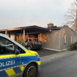 Ein Auto der Polizei steht vor einem Bungalow, der abgebrannt ist In den Kämpen in Bergkamen.