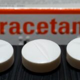 Vor einer Arzneiverpackung liegen Tabletten, die den Wirkstoff Paracetamol enthalten.