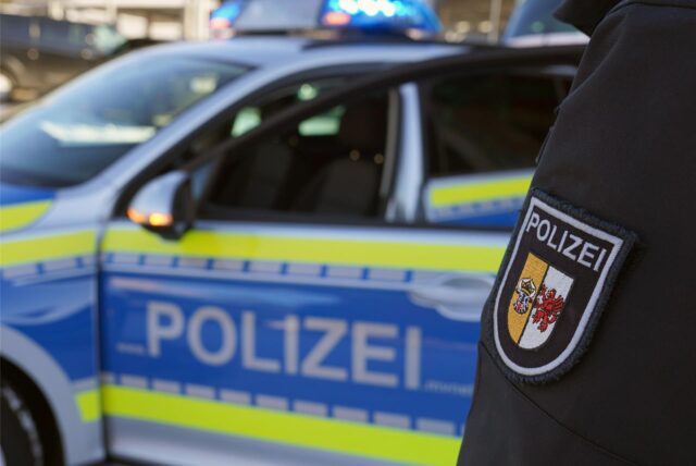 Ein Polizist steht vor einem Polizeiauto.