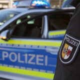 Ein Polizist steht vor einem Polizeiauto.