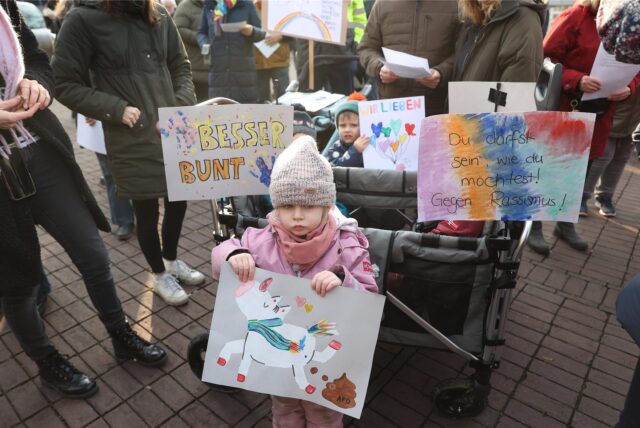 Viele Plakate, ein Kind hält ein gemaltes Einhorn mit einer Botschaft gegen „braune“ Politik.