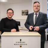 Marc Rostohar vom städtischen Wahlbüro und Wahlleiter Norbert Dahmen mit der Urne für die Wahlbriefe.