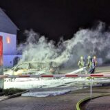 Feuerwehrleute löschen auf dem Parkplatz von Penny in Bergkamen ein brennendes Auto mit Schaum.