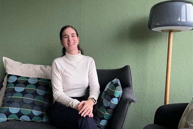 Loubna El Faouzi sitzt auf einem Sofa und lacht.
