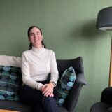 Loubna El Faouzi sitzt auf einem Sofa und lacht.